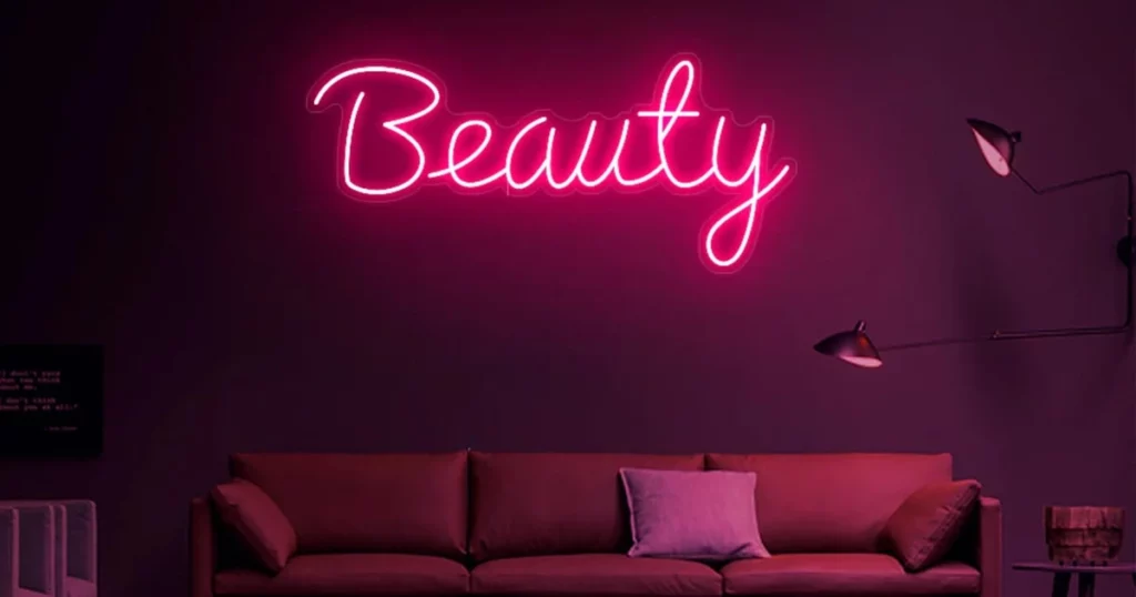 Décoration LED rouge représentant le mot beauté en anglais, sur un mur au dessu d'un canapé