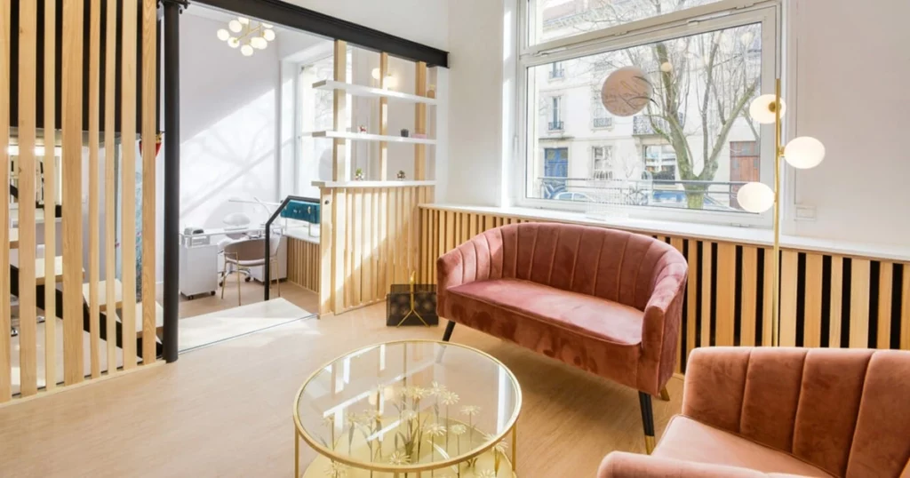 Salle d'attente avec canapés roses tendance et une table basse en verre dorée